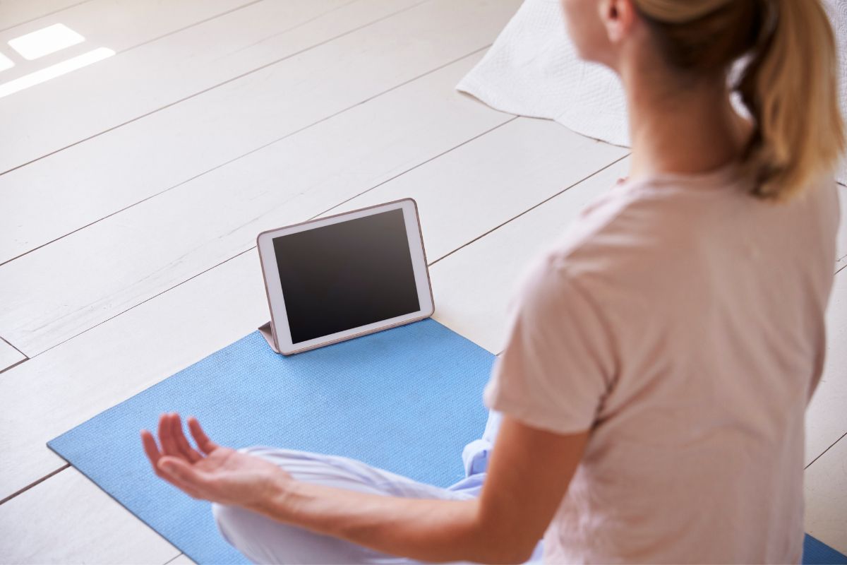 Woman with digital tablet using meditation app in bedroom.