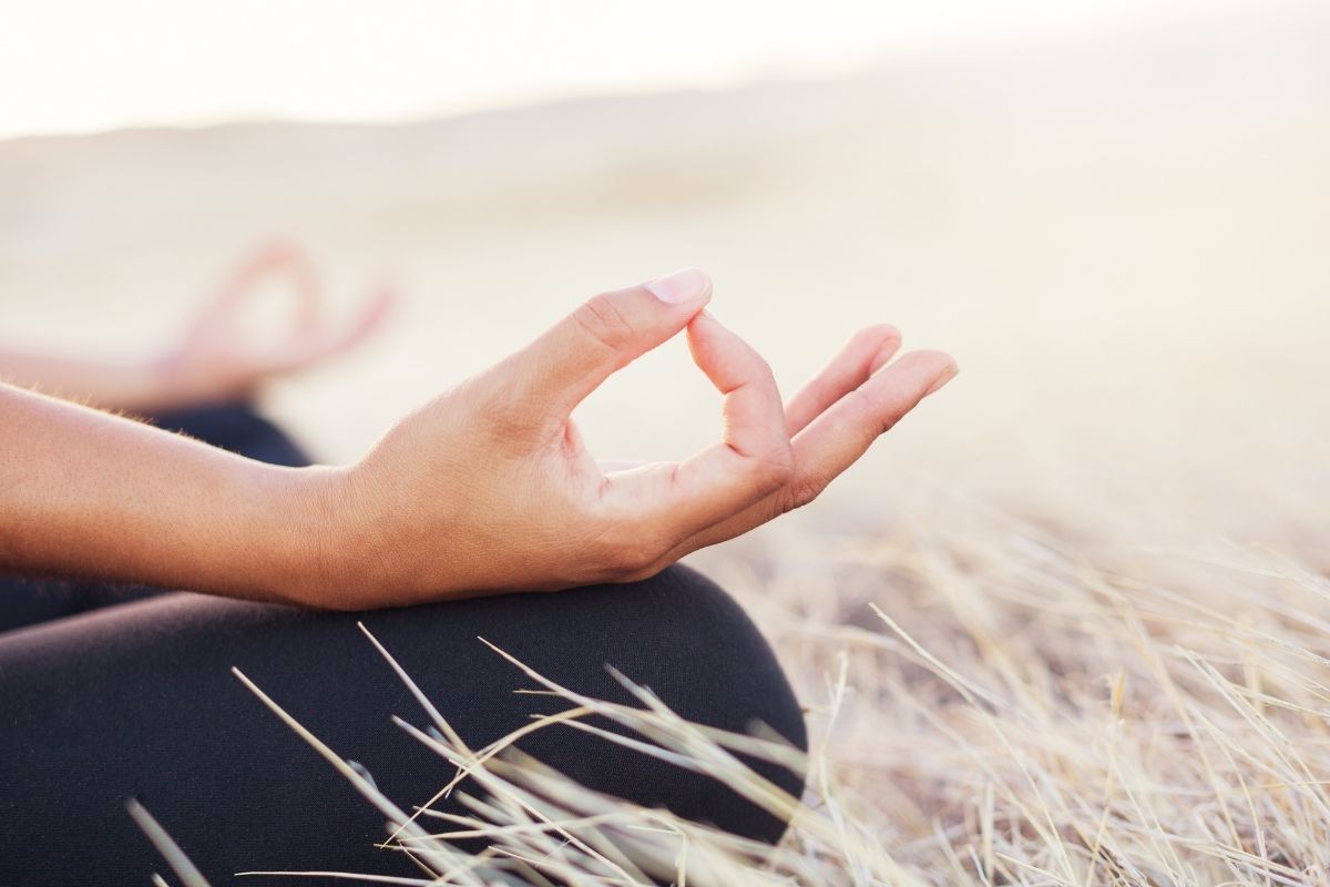 Woman meditating practicing yoga outdoors.