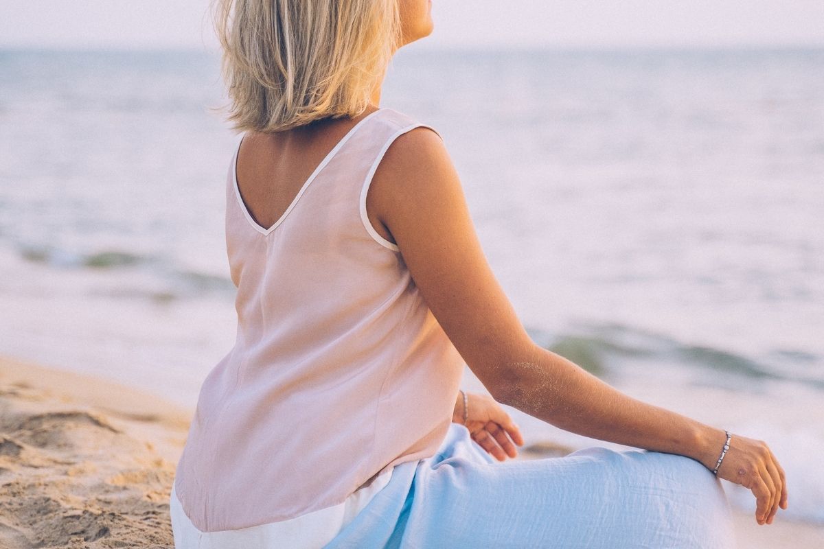 A woman meditating at the beach.