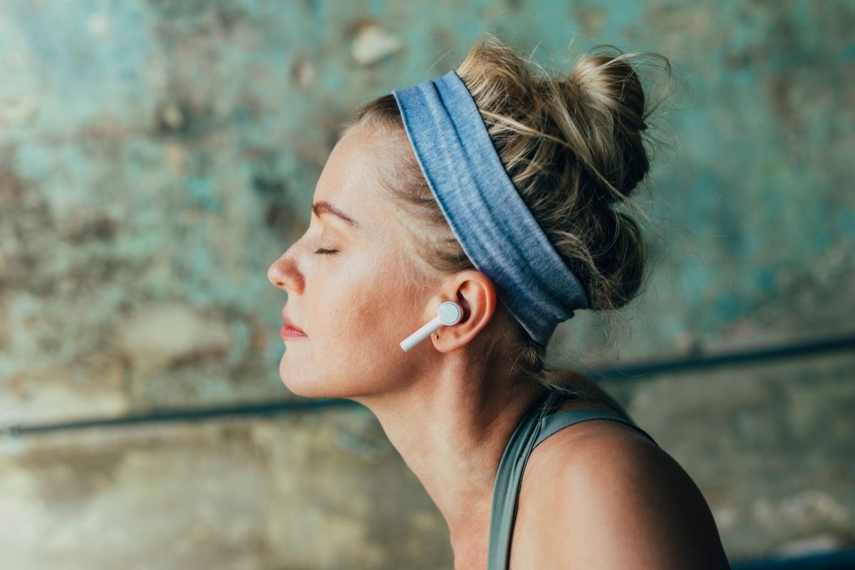 Woman wearing wireless eaphones while listening to guided meditation online.