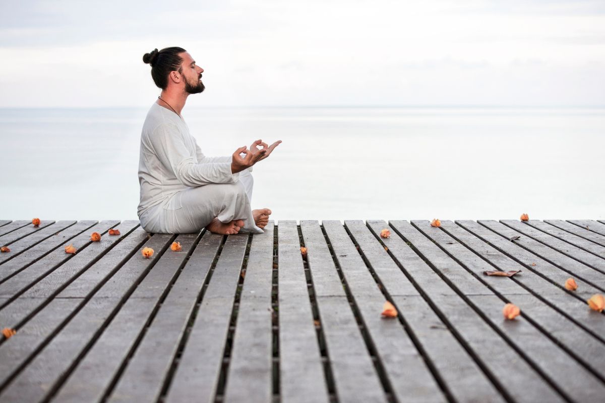 Man meditating on wooden pier.