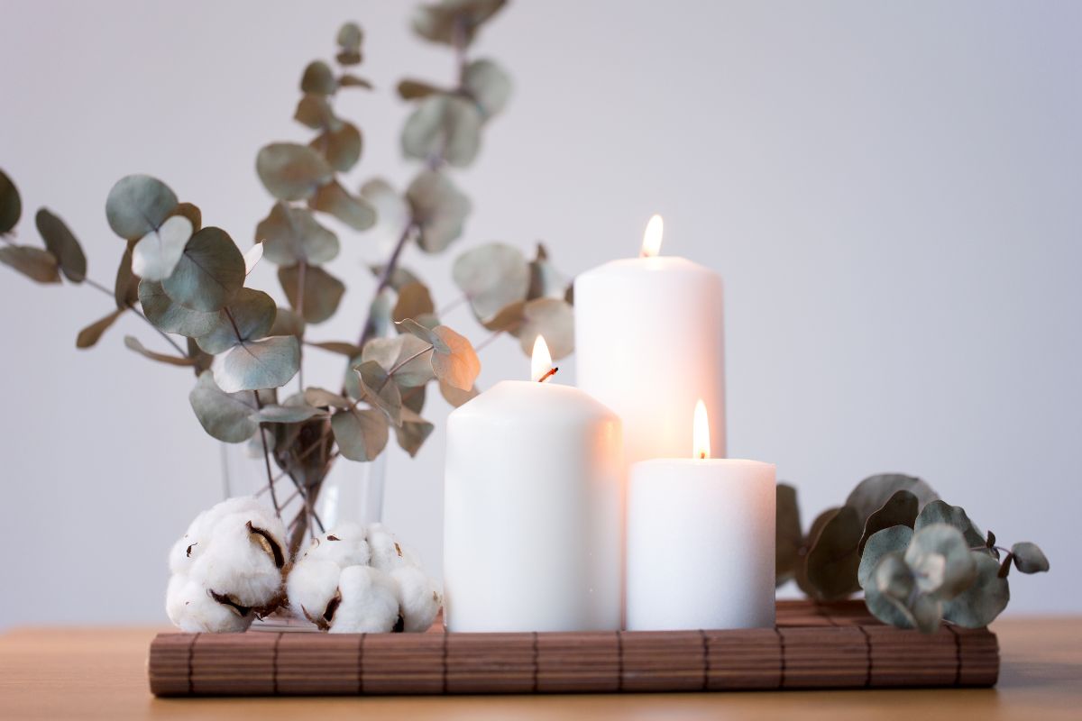 Candles and branches of eucalyptus on table.